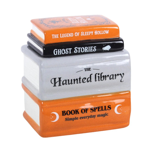 Quemador de aceite y calentador de ceras aromáticas en forma de libros apilados de estética de Halloween y Spooky en naranja, negro y gris vista ángulo sobre fondo blanco.