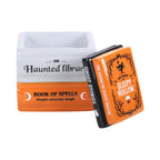 Quemador de aceite y calentador de ceras aromáticas en forma de libros apilados de estética de Halloween y Spooky en naranja, negro y gris vista con tapa abierta sobre fondo blanco.