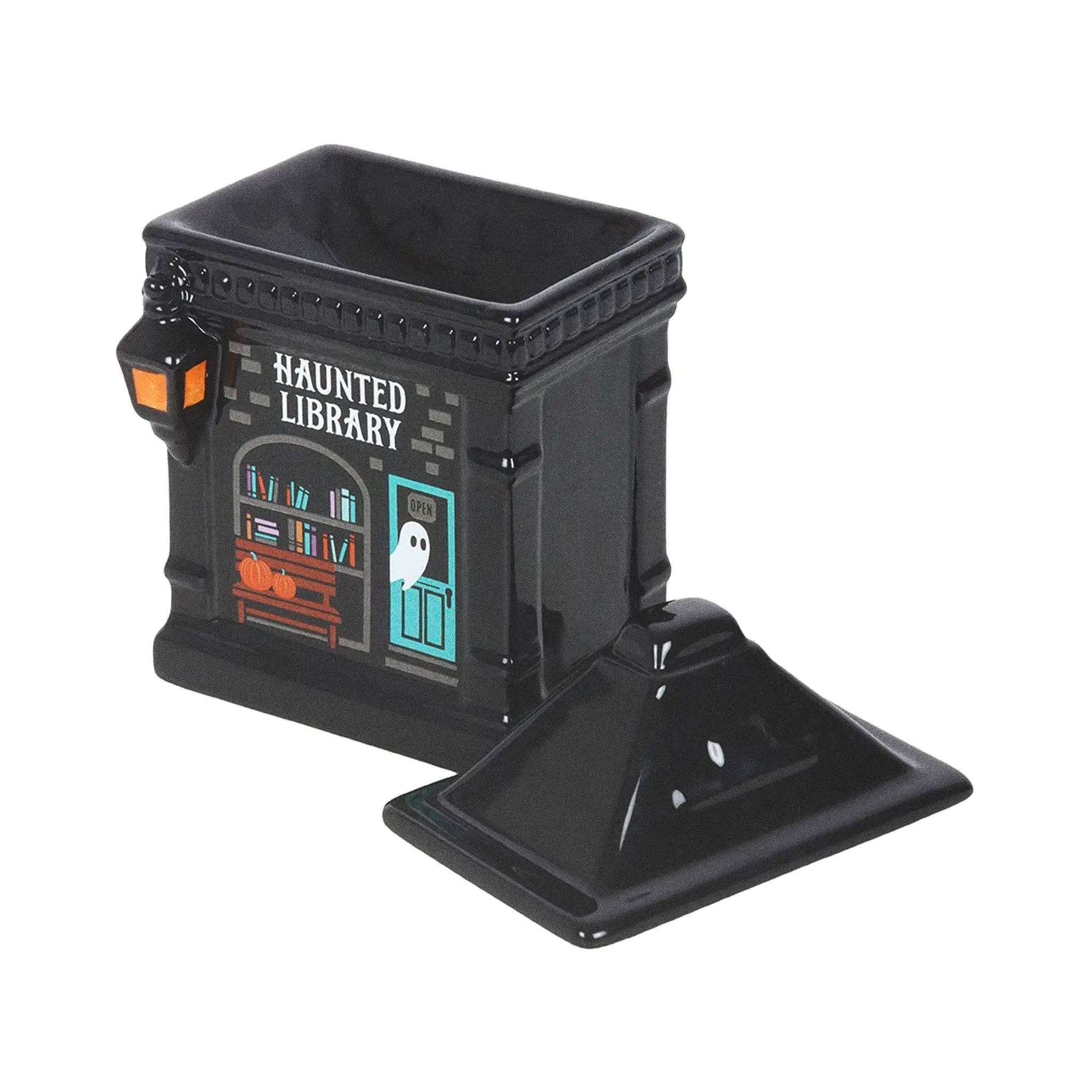 Quemador de aceite y calentador de cera con forma de librería encantada estilo spooky halloween vista con la tapa abierta sobre fondo blanco.
