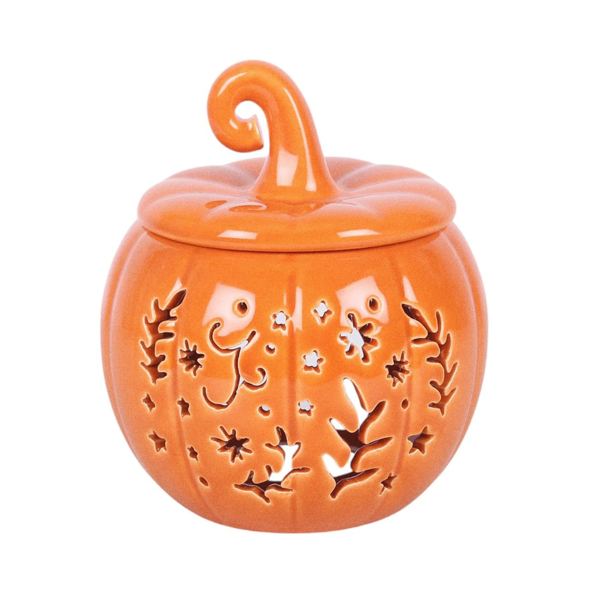 Quemador de aceites esenciales y calentador de cera con diseño naranja en forma de calabaza con motivos otoñales calados en la parte frontal vista frontal sobre fondo blanco.