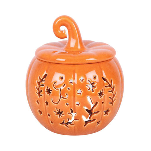 Quemador de aceites esenciales y calentador de cera con diseño naranja en forma de calabaza con motivos otoñales calados en la parte frontal vista frontal sobre fondo blanco.