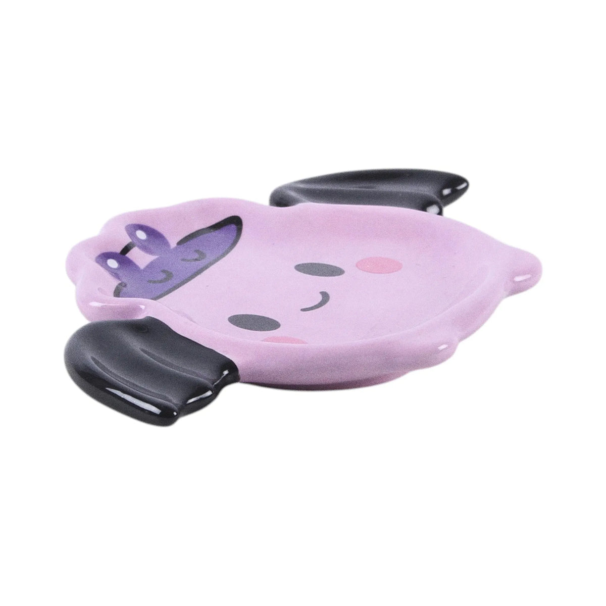 Plato joyero en forma de murciélago con alas estilo kawaii en tonos rosados con carita sonriente vista lateral sobre fondo blanco.