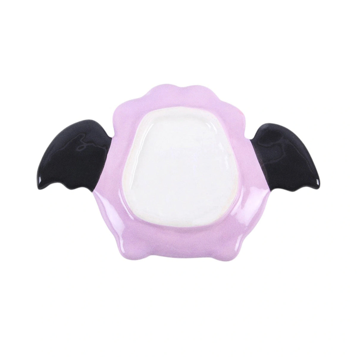 Plato joyero en forma de murciélago con alas estilo kawaii en tonos rosados con carita sonriente vista parte de abajo sobre fondo blanco.