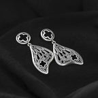 Pendientes con forma de alas de polilla y detalles inspirados en las catedrales góticas fabricados en latón y plata de ley de Restlye vista detalle sobre fondo negro