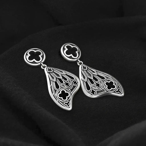 Pendientes con forma de alas de polilla y detalles inspirados en las catedrales góticas fabricados en latón y plata de ley de Restlye vista detalle sobre fondo negro