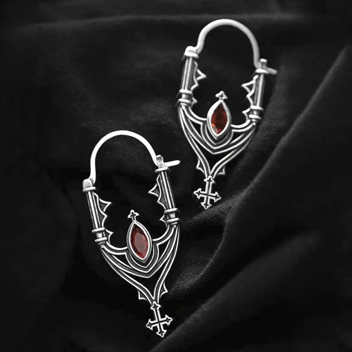 Pendientes inspirados en las catedrales góticas con cruces y piedra roja central estilo whimsigoth fabricado en latón y plata de Restlye vista sobre fondo negro