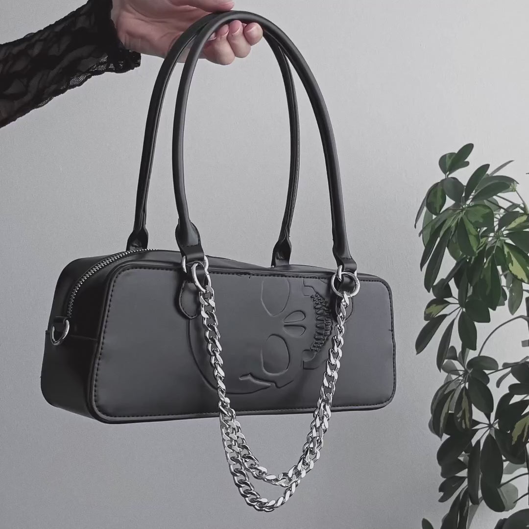 Video de detalles de bolso baguette con relieve en forma de calavera y detalle de cadenas metálicas en el frontal.