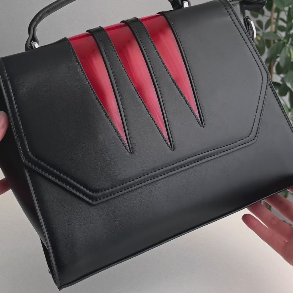 Video en detalle de bolso rígido rectangular con detalles en color rojo en la solapa estilo vamp goth.