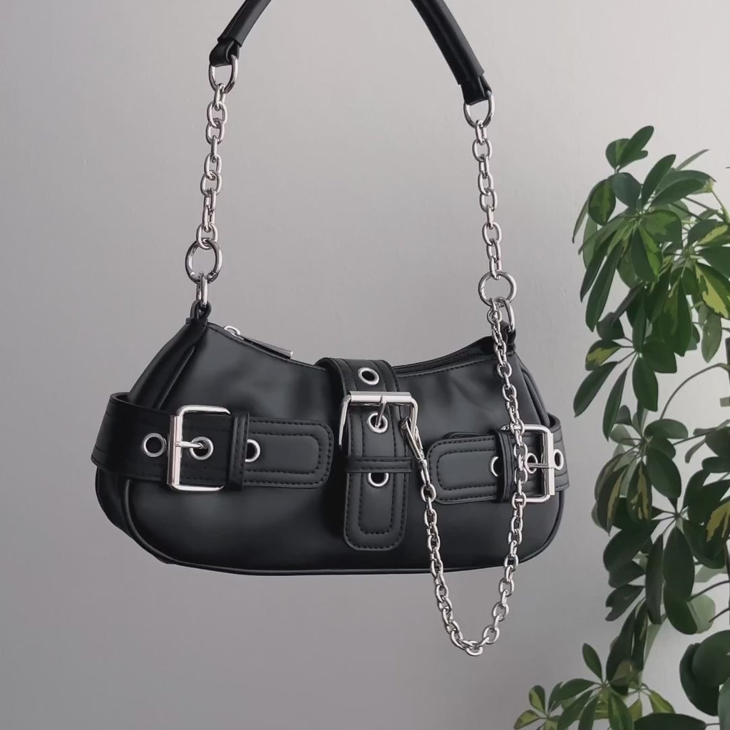 Video de detalle de bolso baguette con hebillas, remaches y cadenas decorativas metálicas estilo y2k.
