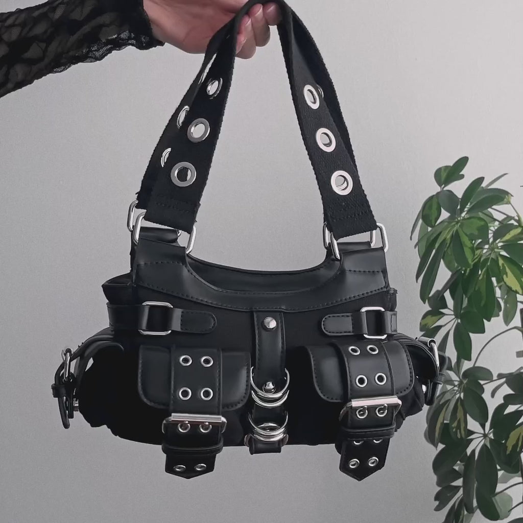 Video de detalles de bolso baguette con remaches y hebillas metálicas estilo y2k con múltiples bolsillos utilitarios.