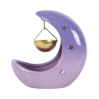 Quemador de aceites esenciales en forma de luna creciente con colores violetas degradados y recipiente colgante para aceite en color dorado vista posterior sobre fondo blanco.