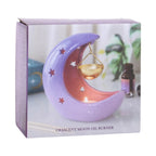 Quemador de aceites esenciales en forma de luna creciente con colores violetas degradados y recipiente colgante para aceite en color dorado vista packaging sobre fondo blanco.