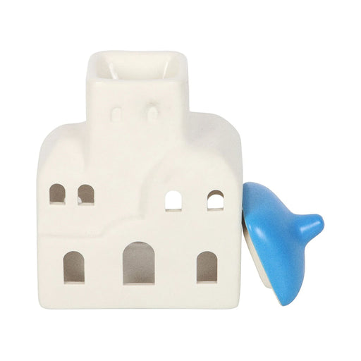 Quemador de aceites esenciales y calentador de cera con forma de casa de Santorini inspirado en Grecia en blanco y azul vista frontal con tapa quitada sobre fondo blanco.