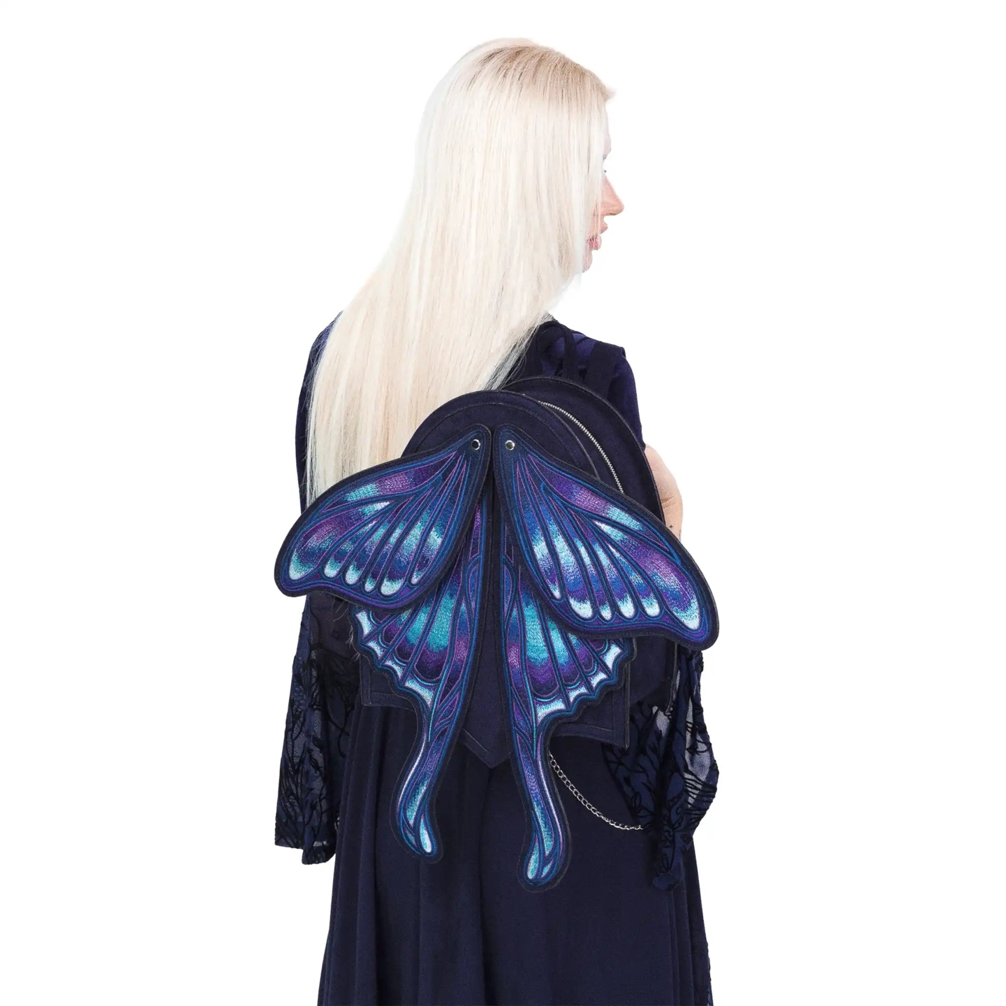 Mochila con alas bordadas en forma de polilla con capacidad de cambiar de posición en tonos azules y violetas estilo whimsigoth y fairycore modelo Sapphire Moth de Restyle vista en hombro de modelo