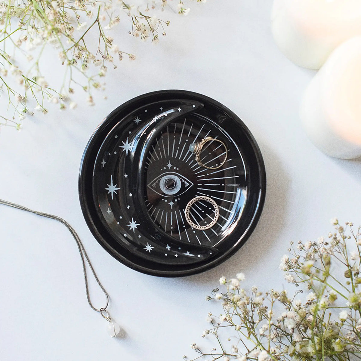 Bandejas apilables en negro con diseño en blanco de ojo que todo lo ve y motivos celestiales estilo witchy vista desde arriba sobre escritorio con decoración al rededor.