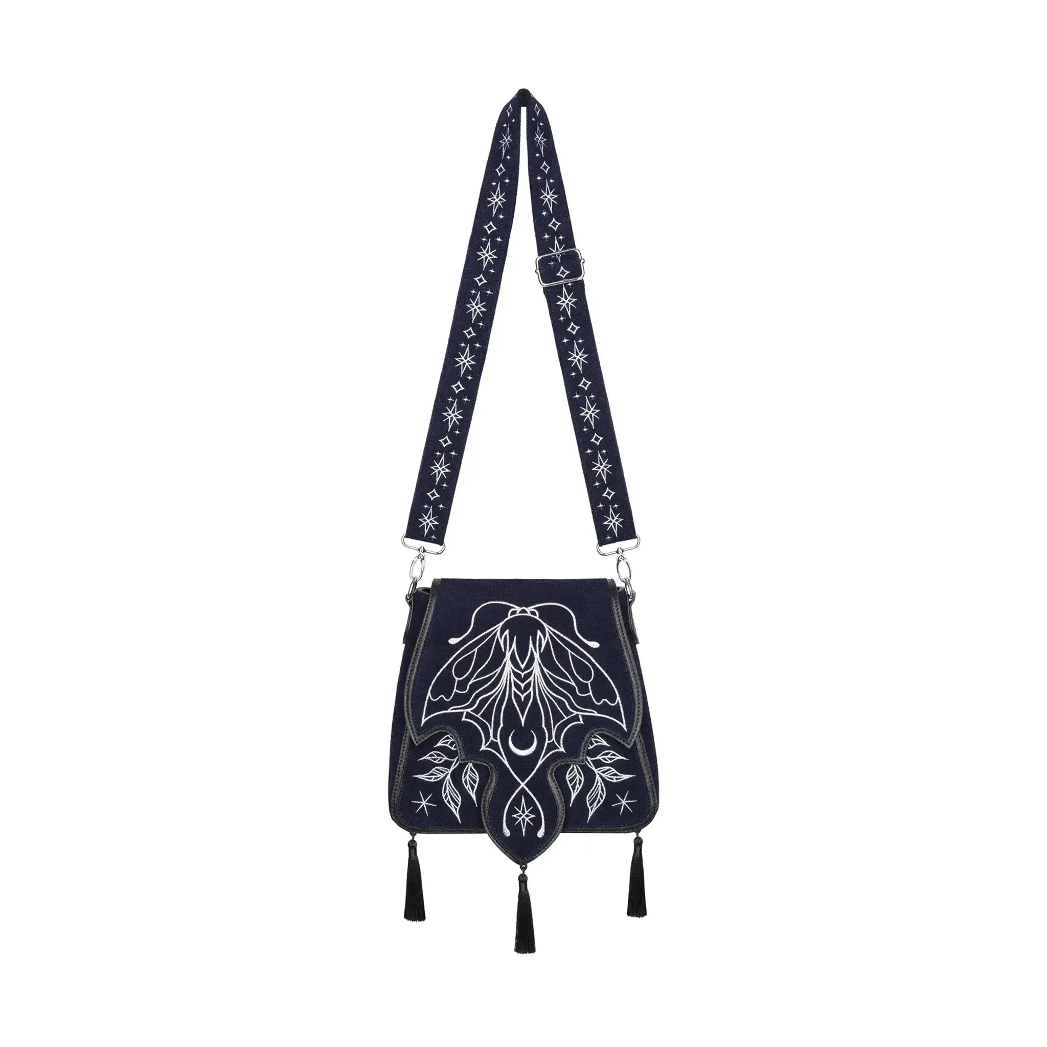 Bolso rígido en azul medianoche con ribetes en negro, bordado en tonos plateados con un diseño celestial de polilla, luna, estrellas y vegetación estilo whimsigoth. Borlas decorativas en la solapa. Vista frontal completa con correa