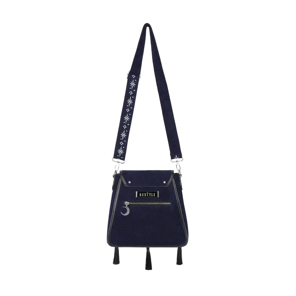 Bolso rígido en azul medianoche con ribetes en negro, bordado en tonos plateados con un diseño celestial de polilla, luna, estrellas y vegetación estilo whimsigoth. Borlas decorativas en la solapa. Vista posterior completa con correa 