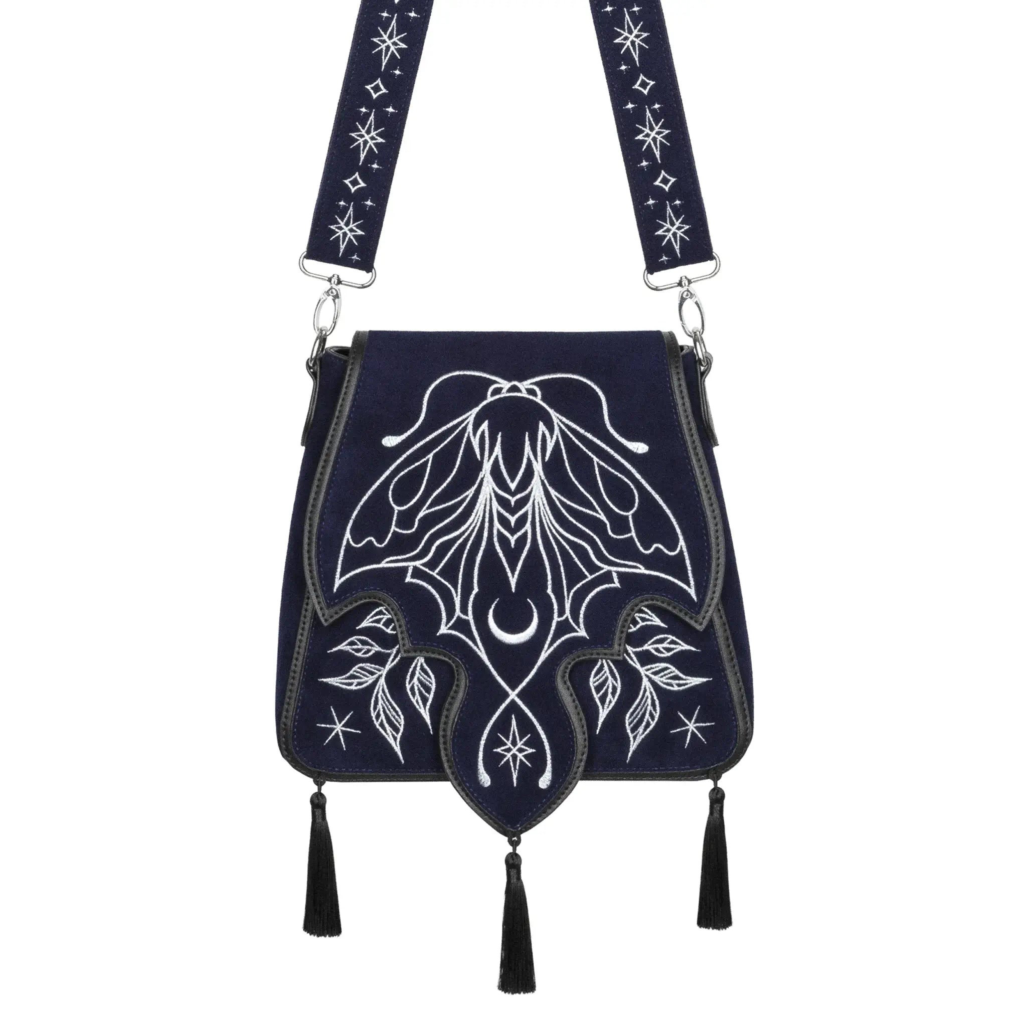 Bolso rígido en azul medianoche con ribetes en negro, bordado en tonos plateados con un diseño celestial de polilla, luna, estrellas y vegetación estilo whimsigoth. Borlas decorativas en la solapa. Vista frontal con borlas y detalle de correa