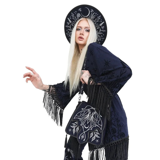 Bolso rígido en azul medianoche con ribetes en negro, bordado en tonos plateados con un diseño celestial de polilla, luna, estrellas y vegetación estilo whimsigoth. Borlas decorativas en la solapa. Vista con modelo en el hombro