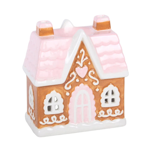 Quemador de aceite y calentador de cera en forma de casita de jengibre estilo navideño en marrón, blanco y rosa vista ángulo sobre fondo blanco.