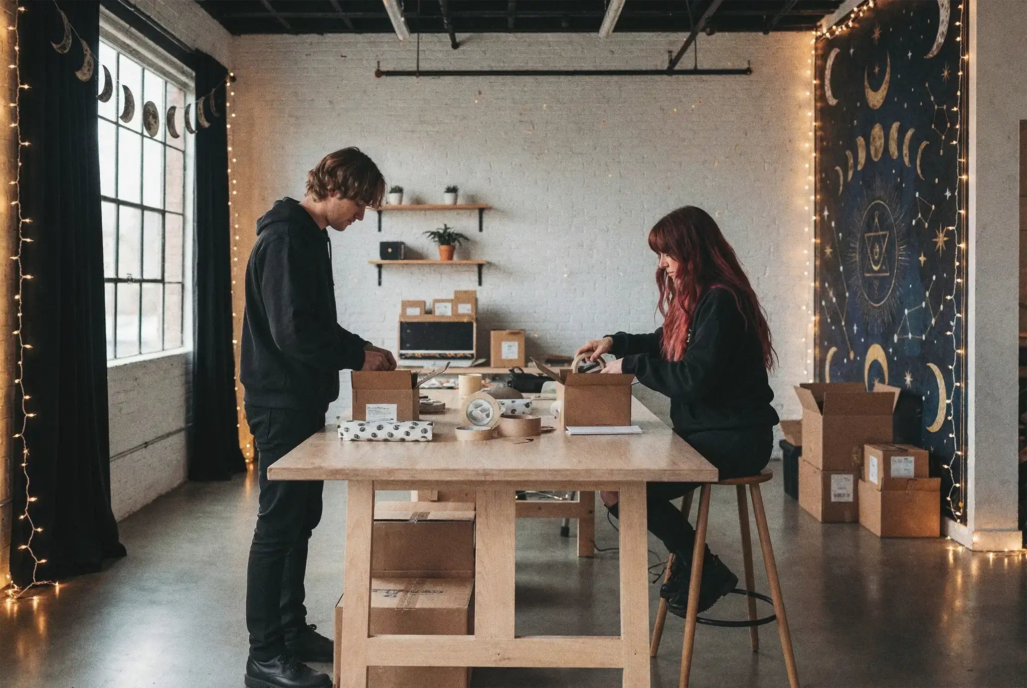 Dos personas trabajando en la oficina de GloryTheShop empaquetando pedidos en una mesa