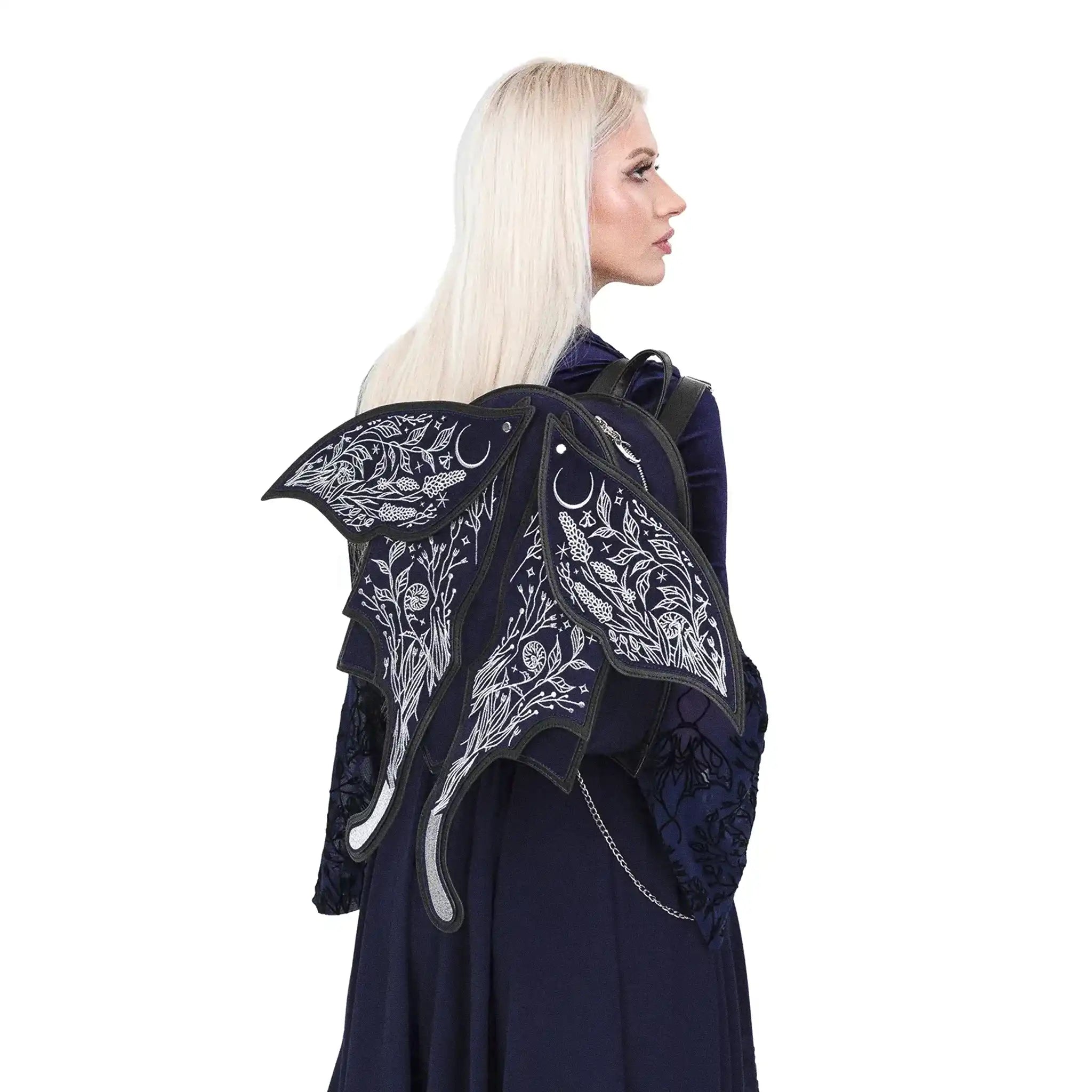 Mochila con alas móviles bordadas en plateado sobre un fondo azul medianoche con detalles contrastados en negro estética whimsigoth y fairycore modelo Umbra Noctis de Restyle vista con modelo en hombro