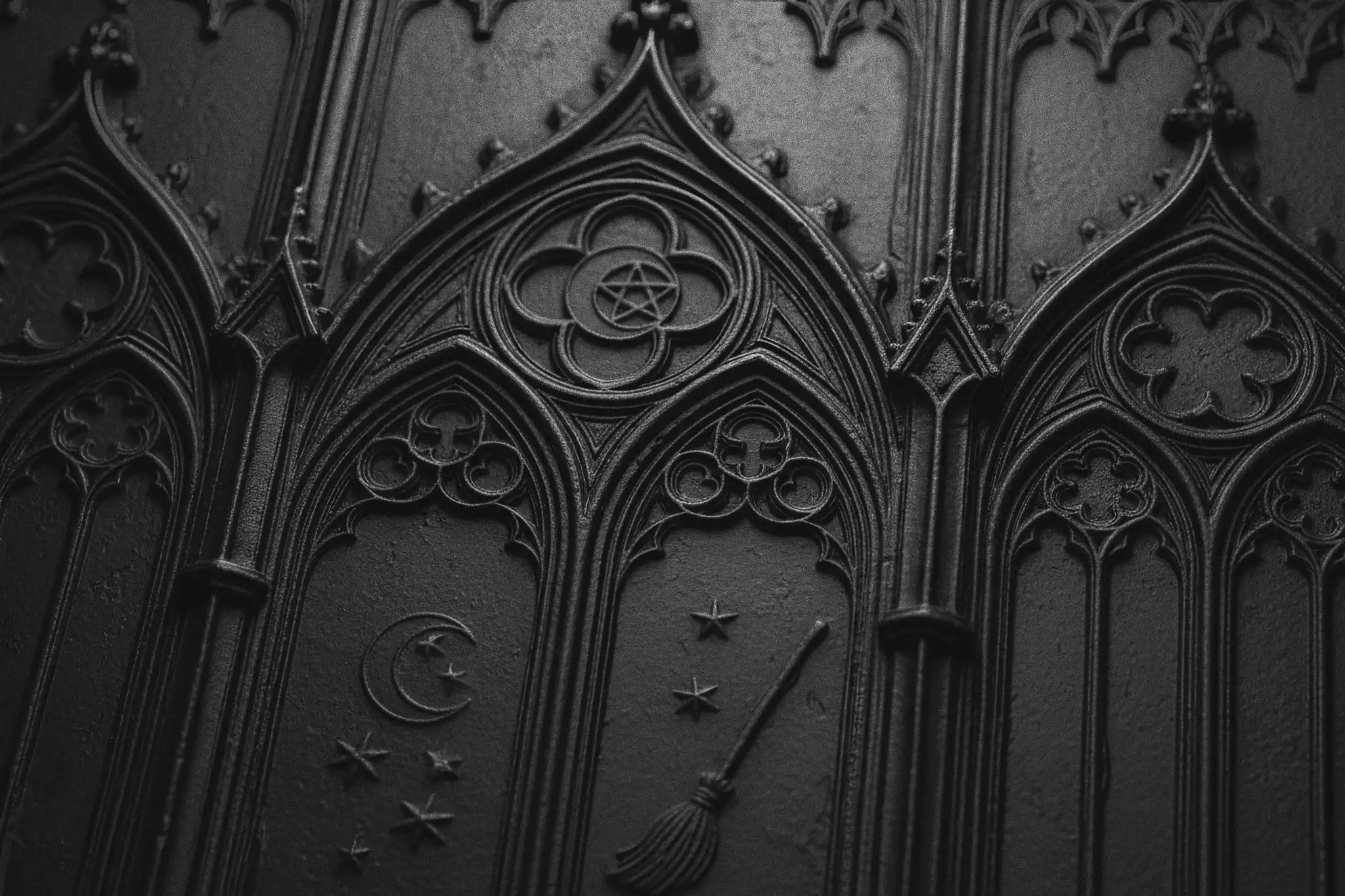 Close-up of a soft black texture with deeply embossed old gothic church and witchy motifs.
