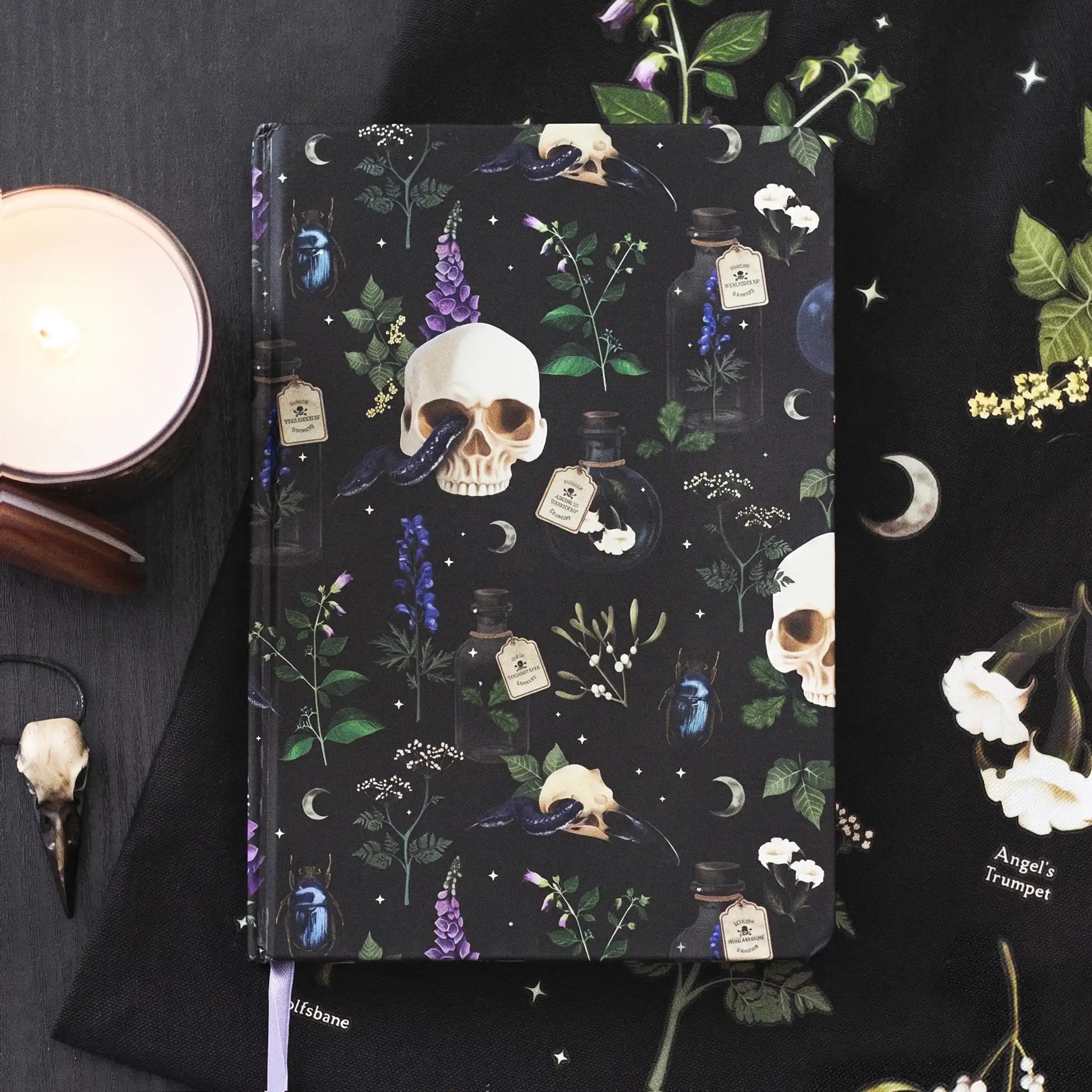 Libreta estilo witchy apoyada sobre tela con decoración al rededor.