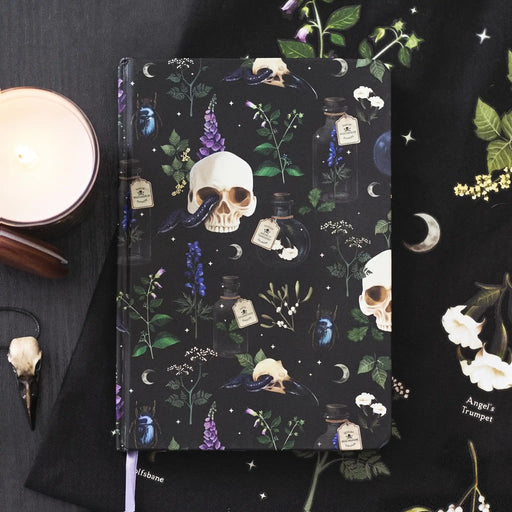 Libreta estilo witchy apoyada sobre tela con decoración al rededor.