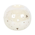 Quemador de aceites esenciales y calentador de ceras aromáticas con forma de bola con estrellas caladas en color blanco iridiscente vista frontal sobre fondo blanco.