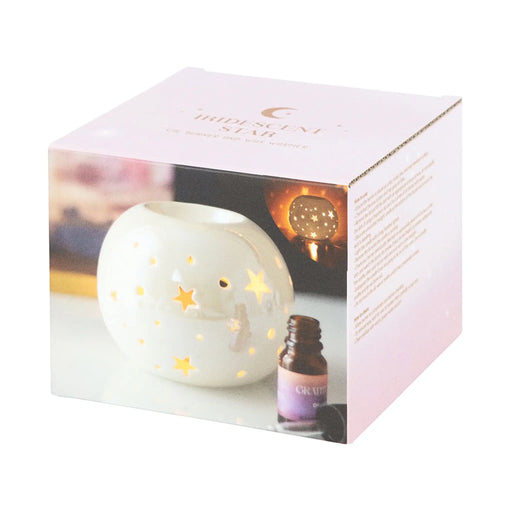 Quemador de aceites esenciales y calentador de ceras aromáticas con forma de bola con estrellas caladas en color blanco iridiscente vista packaging sobre fondo blanco.